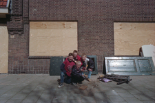852417 Afbeelding van enkele buurtkinderen bij een van de dichtgetimmerde en voor sloop bestemde huizen aan de ...